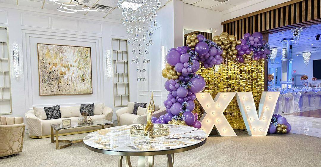 A lounge area with a gold shimmer wall, balloon garland and marquee XV letters