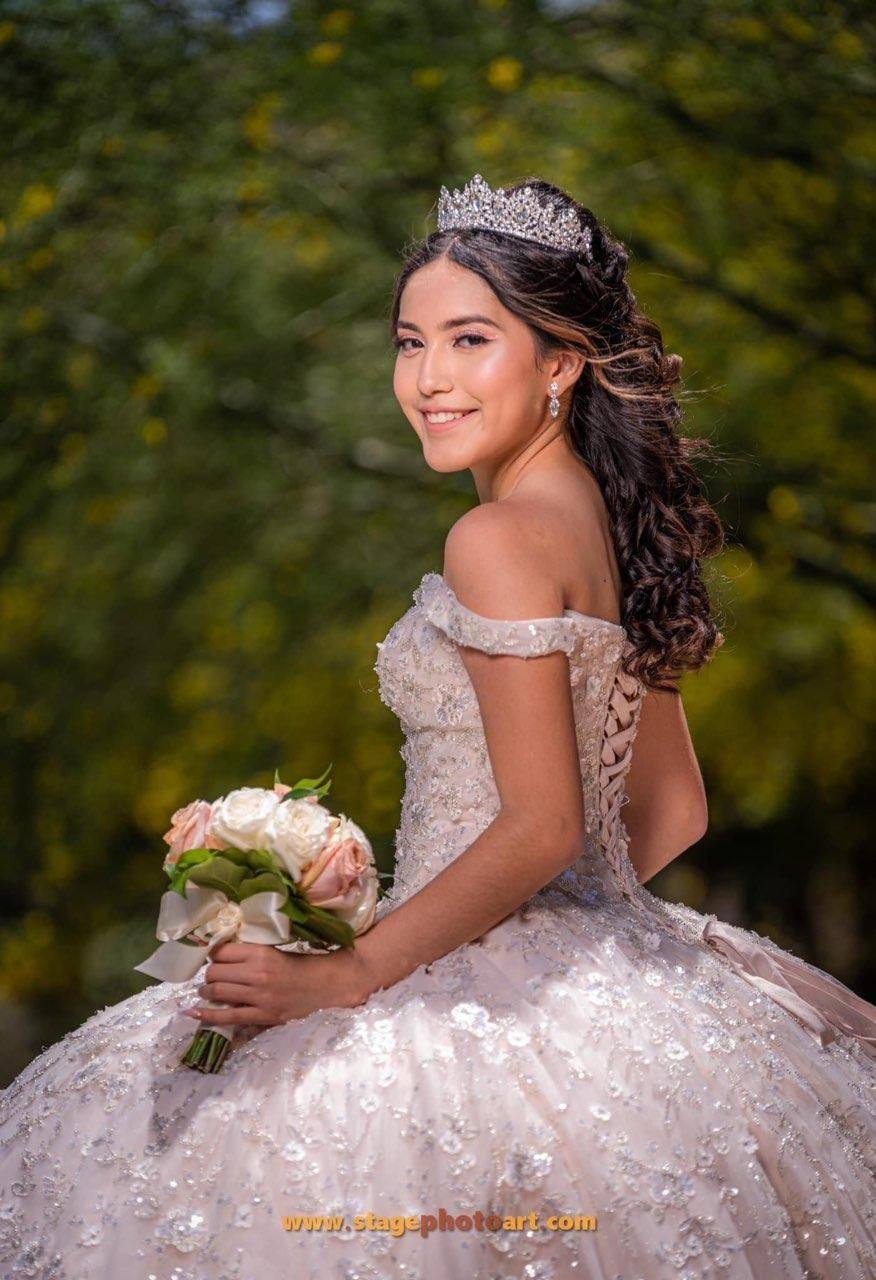 A quinceañera in a blush ball gown holding a bouquet
