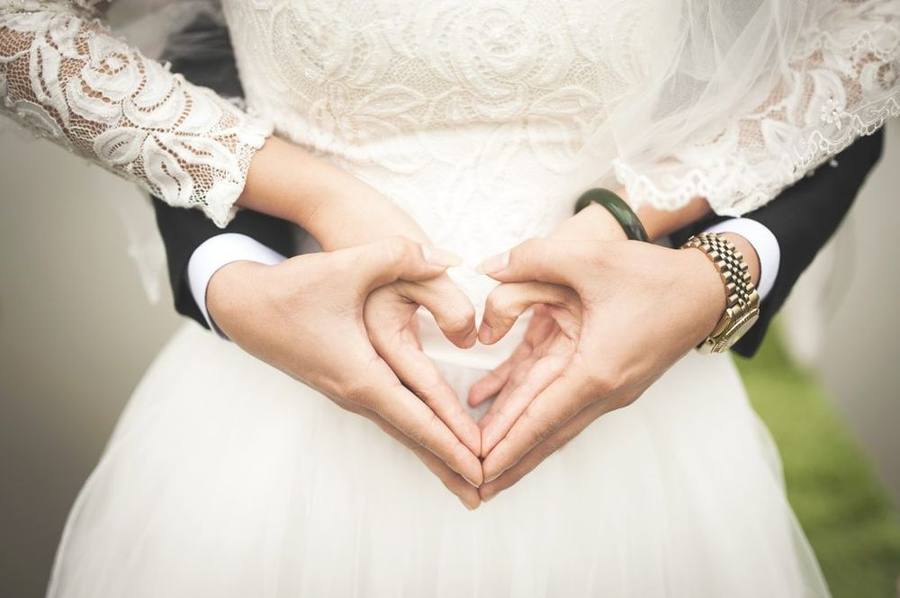 A bride and groom forming a heart with their hands on their wedding day